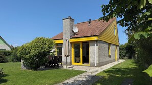 A house with a stone facade, yellow trim, and a chimney. - 3 bedroom accommodation in Julianadorp aan Zee (Julianadorp aan Zee)