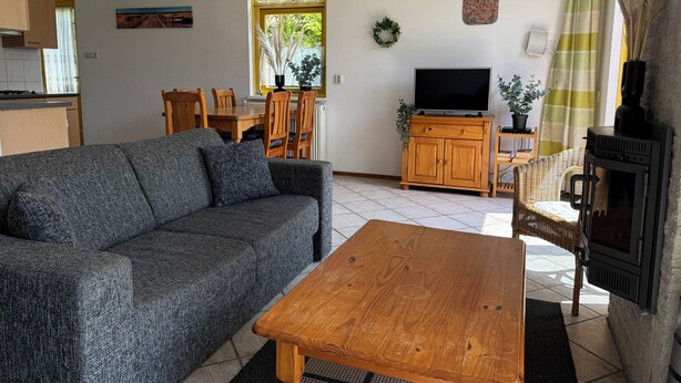 A living room with a sofa, a wooden coffee table, a TV, and a fireplace. - 3 bedroom accommodation in Julianadorp aan Zee (Julianadorp aan Zee)