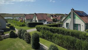 A row of houses with sloped roofs, likely equipped with solar panels, set in a green, hilly area. - 3 bedroom accommodation in Julianadorp aan Zee (Julianadorp aan Zee)