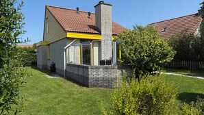 A house with a stone chimney, a yellow window frame, and a red-tiled roof. - 3 bedroom accommodation in Julianadorp aan Zee (Julianadorp aan Zee)