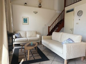 A living room with two patterned sofas, a small wooden coffee table, a fireplace, and a staircase.