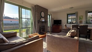 A living room with a fireplace, a television, and a dining area with chairs and a table.