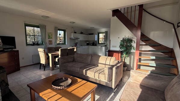 A living room with a sofa, a dining table, and a kitchen in the background.