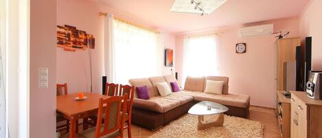 A living room with a dining table, sofa, and a TV stand.