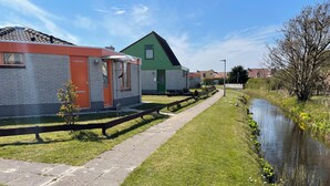 A narrow pathway beside a water canal with houses on one side. - 3 bedroom accommodation in Julianadorp aan Zee (Julianadorp aan Zee)