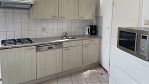 A modern kitchen with light wood cabinets, a stainless steel stove, a sink, and a built-in microwave. - 3 bedroom accommodation in Julianadorp aan Zee (Julianadorp aan Zee)