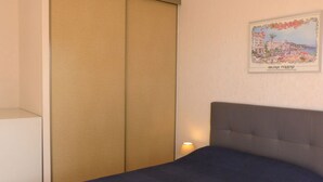 Una habitación de hotel con cama, armario y un cuadro colgado en la pared.