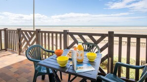 Una mesa con sillas en una terraza con vista a la playa.