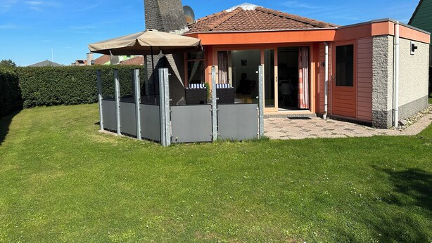 A house with a covered patio, a chimney, and a small attached structure.