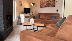 A living room with a fireplace, a sofa, a coffee table, a TV, and a painting on the wall.