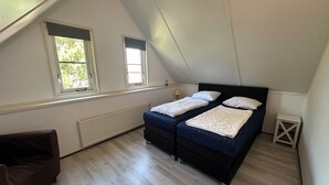 Una camera da letto con due letti, un termosifone e una finestra.