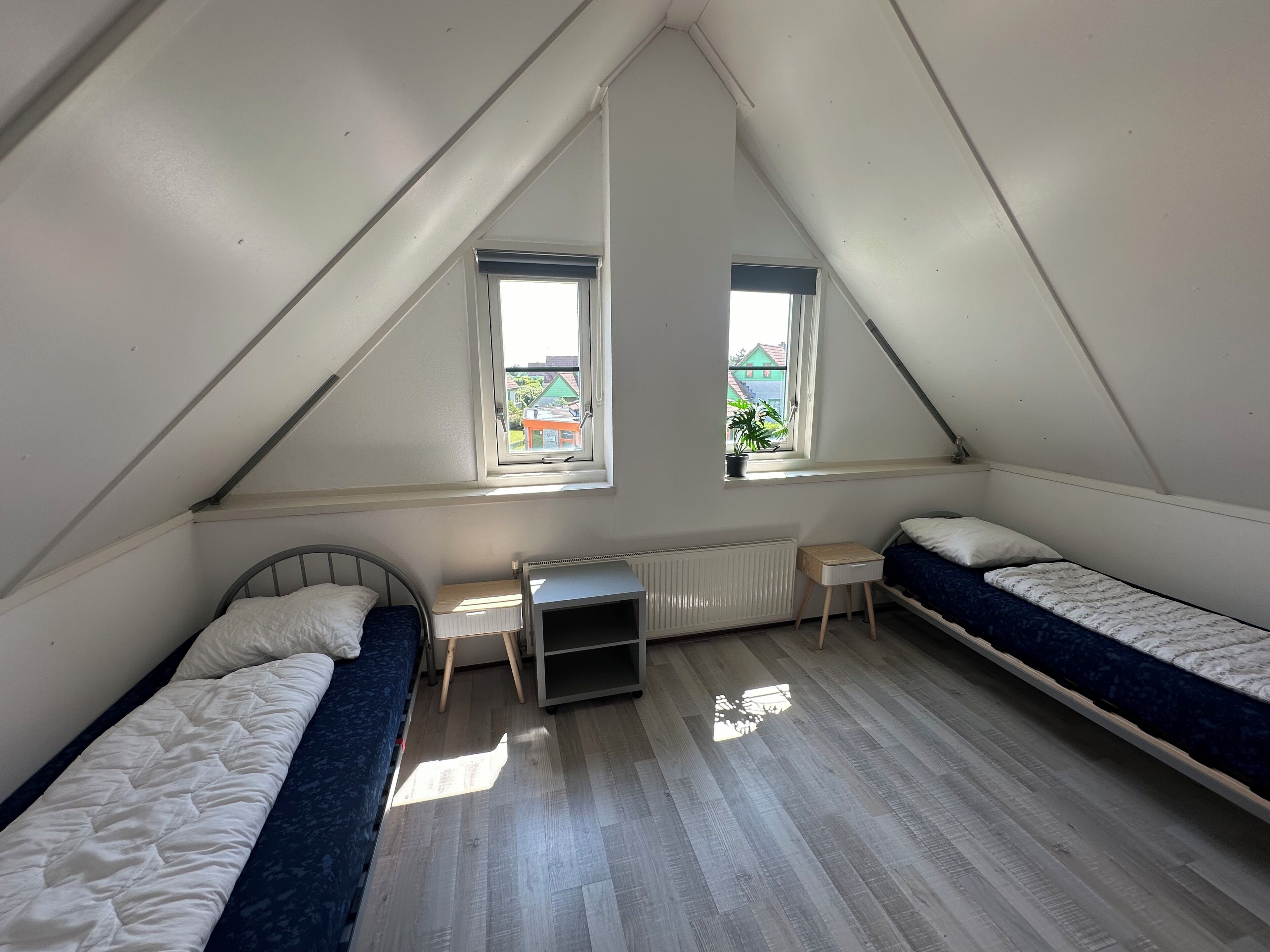 Ein Schlafsaalzimmer mit zwei Einzelbetten, einem kleinen Schreibtisch und einer Heizung.