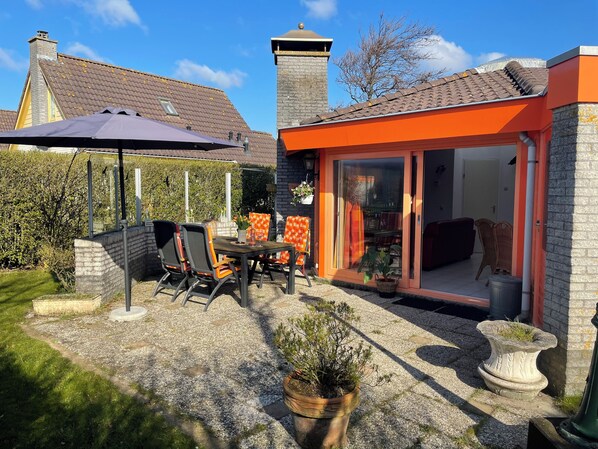 A patio area with a table and chairs, a covered seating area, and a glass door leading to an interior space.