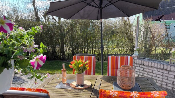 An outdoor patio with a table, chairs, and an umbrella. - 3 bedroom accommodation in Julianadorp (Julianadorp)