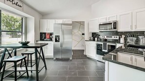 A modern kitchen with white cabinets, stainless steel appliances, and a black countertop. - NAS Jax Pool Hot-tub Gameroom Message for Spring (Jacksonville)