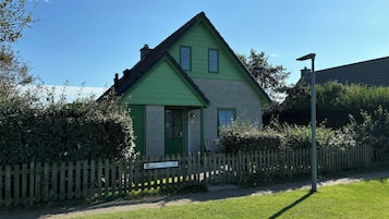 Une maison à deux étages, avec une façade verte et un petit porche à l’avant.