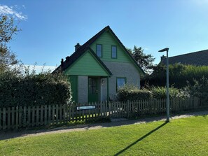 A two-story house with a green exterior and a small front porch.