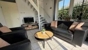 Una sala de estar moderna con un sofá, sillones, una mesa de centro y un televisor.