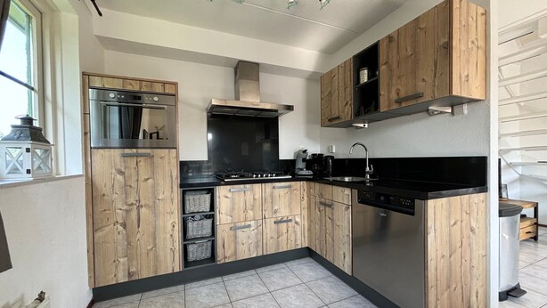 Una cocina moderna con armarios de madera, electrodomésticos de acero inoxidable y suelo de baldosas.
