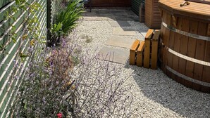 A rustic building with a sloped roof, a wooden deck, and a hot tub. - Jossies Snug - peaceful, private garden/hot tub, swimming lake, Spa and Wellness (Bletchingley)