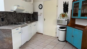 A compact kitchen with white cabinets, a gas stove, a microwave, and a trash bin. - 3 bedroom accommodation in Julianadorp aan Zee (Julianadorp aan Zee)
