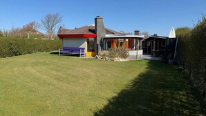 A house with a well-maintained lawn, a small patio area, and a garage. - 3 bedroom accommodation in Julianadorp aan Zee (Julianadorp aan Zee)