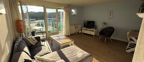 Ett vardagsrum med en soffa, ett soffbord, en tv och en matplats med stolar.