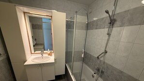 Ein modernes Badezimmer mit einer Duschkabine, einem Waschbecken mit Spiegel und einer Badewanne.
