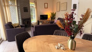 Una sala de estar con chimenea, sofás, televisor y una mesa de comedor con decoraciones de estrellas de mar.