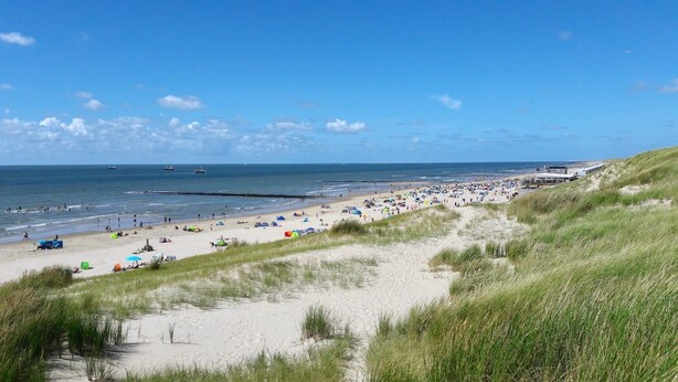 Una playa con arena, dunas y el mar.