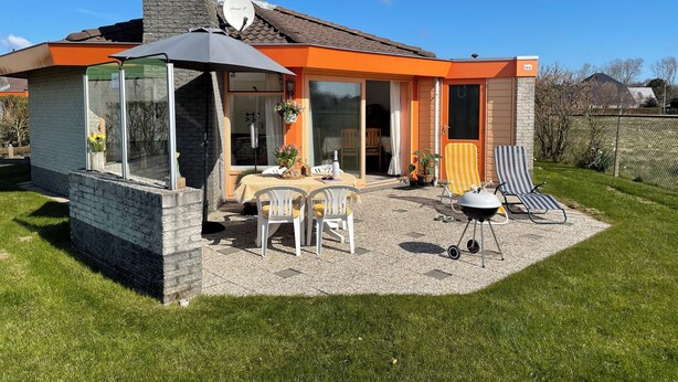 Una casa con un patio attrezzato, che include tavolo, sedie e un barbecue.