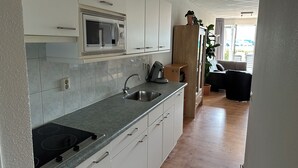 Una cocina moderna con armarios blancos, un microondas integrado, un fregadero y una estufa.