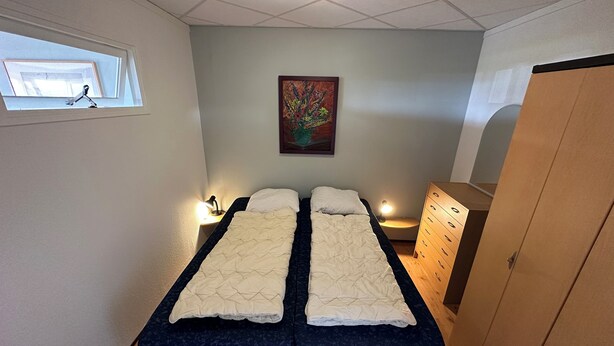 A room with two beds, a wooden dresser, a painting on the wall, and a window with a view. - 2 bedroom accommodation in Julianadorp aan Zee (Julianadorp aan Zee)