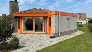 Een modern huis met een stenen gevel, oranje accenten en een pannendak.