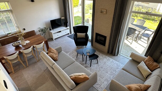 Een moderne woonkamer met een bank, een televisie, een open haard en een eethoek met een tafel en stoelen.