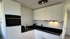 Een kleine keuken met witte kasten, een zwart aanrecht en een ingebouwde oven.