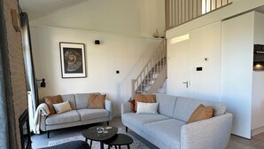 Een moderne woonkamer met twee banken, een salontafel en een trap naar een hoger gelegen verdieping.