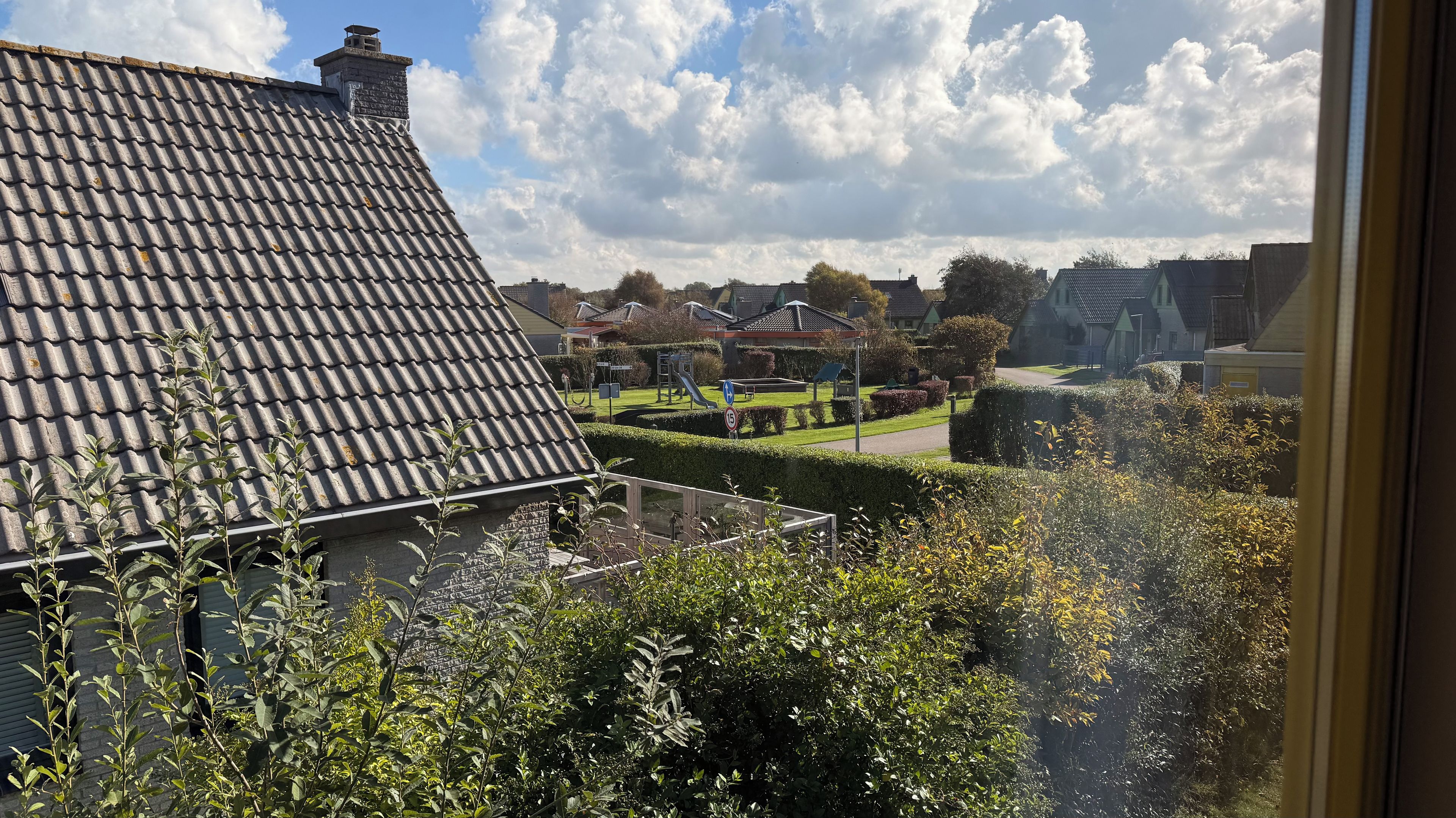 Un quartier résidentiel avec des toits en tuiles, une aire de jeux et des haies bien entretenues.