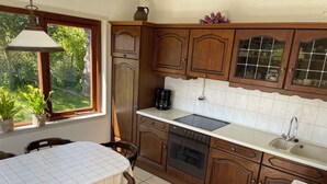 Una cucina con mobili in legno, un piano di lavoro bianco, una lavastoviglie Bosch e una finestra con piante.