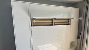 Een kamer met een witte kast, een houten plank en een raam met gordijnen.