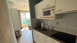 Een moderne keuken met witte kasten, een zwart aanrecht en een ingebouwde magnetron.
