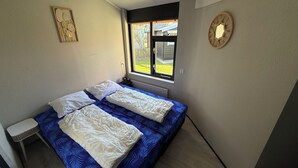 Ein Schlafzimmer mit Bett, Nachttisch, Fenster und Wanddekoration.
