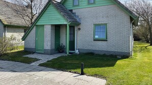 A two-story house with a green door and windows, a small porch, and a brick exterior. - 2 bedroom accommodation in Julianadorp aan Zee (Julianadorp aan Zee)