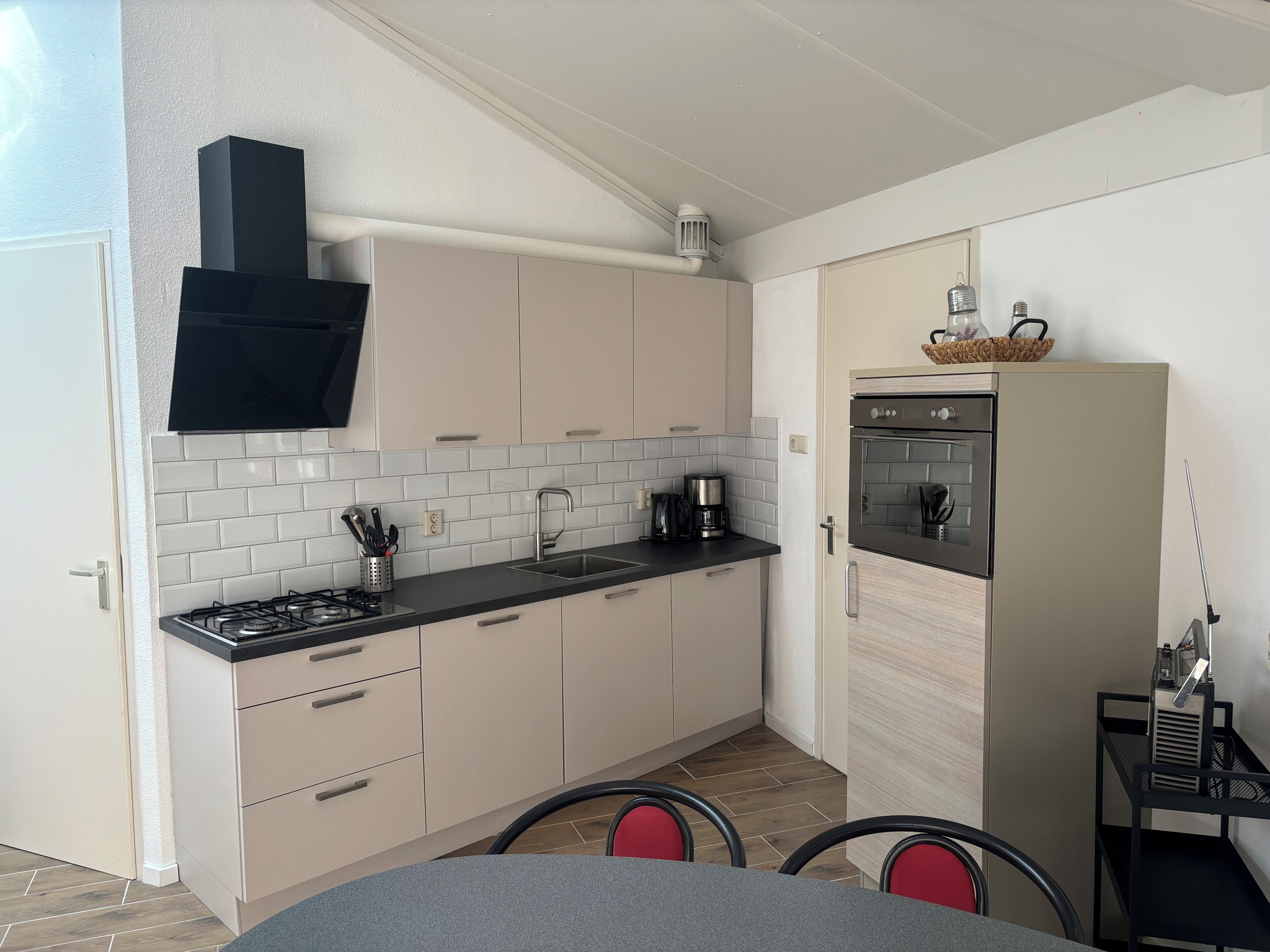 A compact kitchen with a gas stove, sink, and a built-in oven. There are cabinets and a countertop with a coffee maker.
