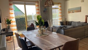 A dining area with a wooden table, black chairs, and a large window with curtains. - 3 bedroom accommodation in Julianadorp aan Zee (Julianadorp aan Zee)