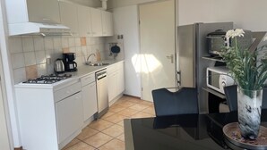 A compact kitchen with white cabinets, a gas stove, a coffee maker, and a microwave.