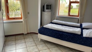 A bedroom with a bed, a television, and a window with curtains. - 2 bedroom accommodation in Julianadorp aan Zee (Julianadorp aan Zee)