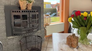 A room with a fireplace, a wicker basket, and a vase with flowers. - 2 bedroom accommodation in Julianadorp aan Zee (Julianadorp aan Zee)