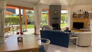 Un'ampia zona giorno con camino, televisione e tavolo da pranzo con sedie.