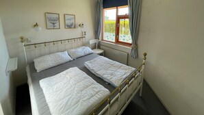 Una camera da letto con un letto, una sedia, una finestra con tende e luci a parete.
